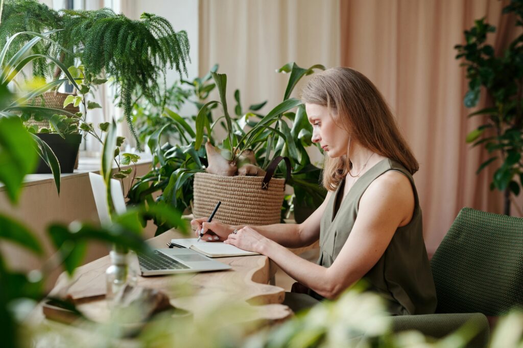 woman sat working at desk covered in plants on our article on ESG reporting